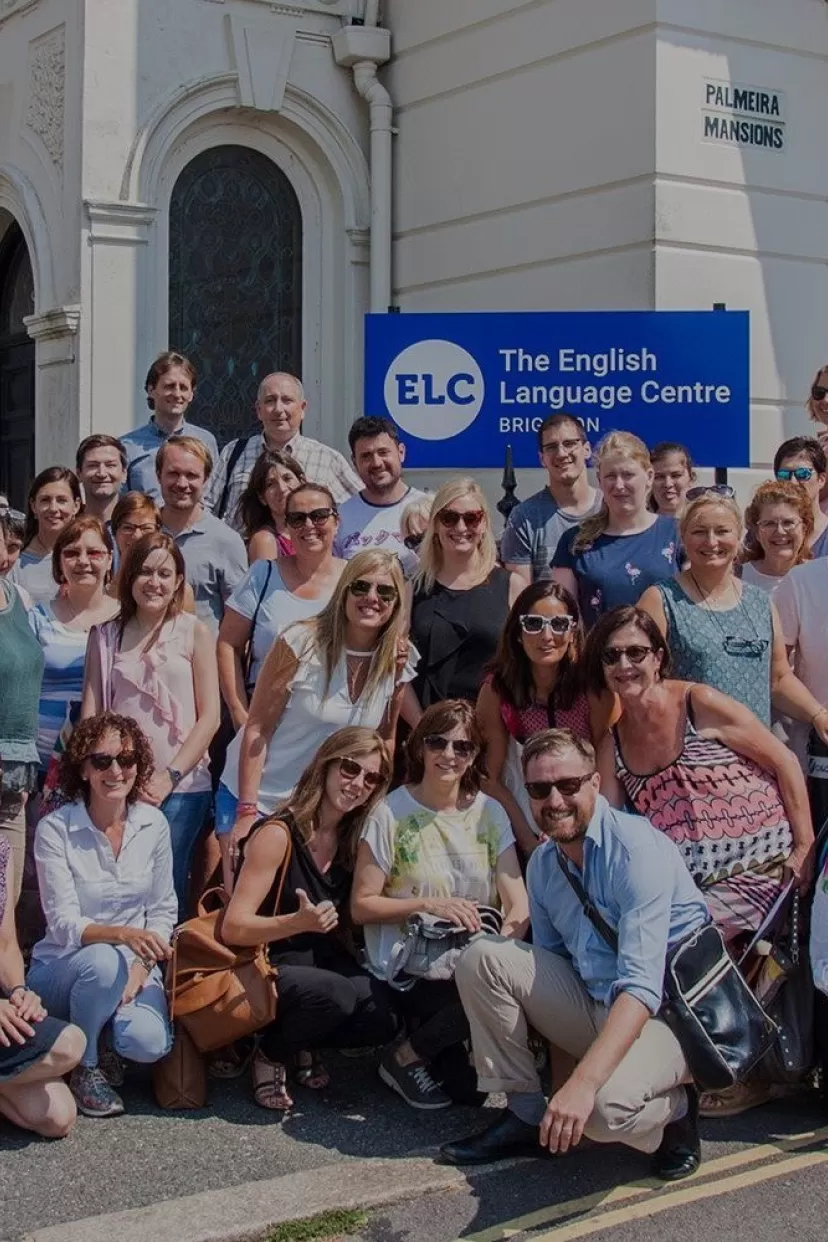 A group photo of a large number of very happy-looking teachers of English who have been attending a summer teachers' course designed for internationally based teachers of English to help them improve various aspects of their methodology and teaching skills. The photo is taken on the pavement outside ELC English language school in Brighton where the course took place.