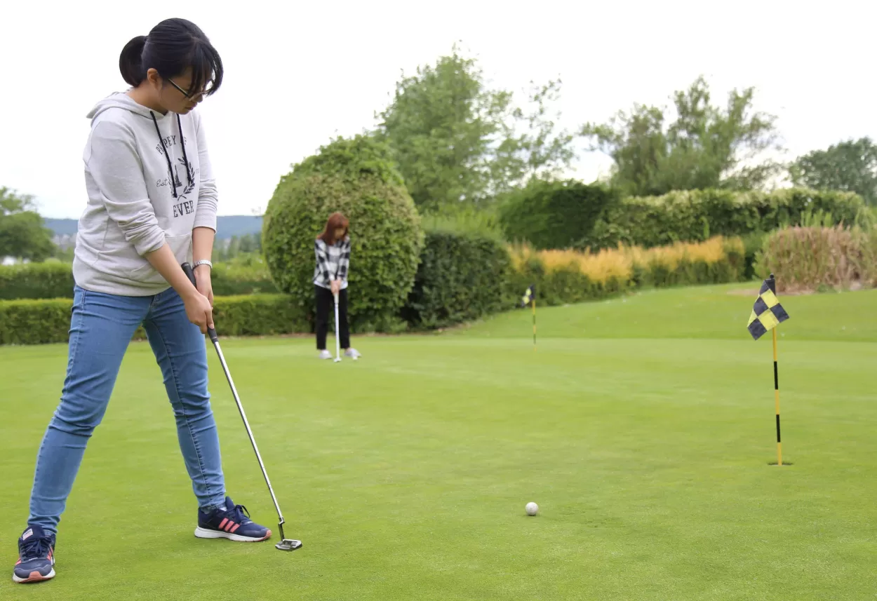 Two English language students enjoy some putting practise during the golf activity they have booked as part of their English plus activity programme at the English language centre in Eastbourne.