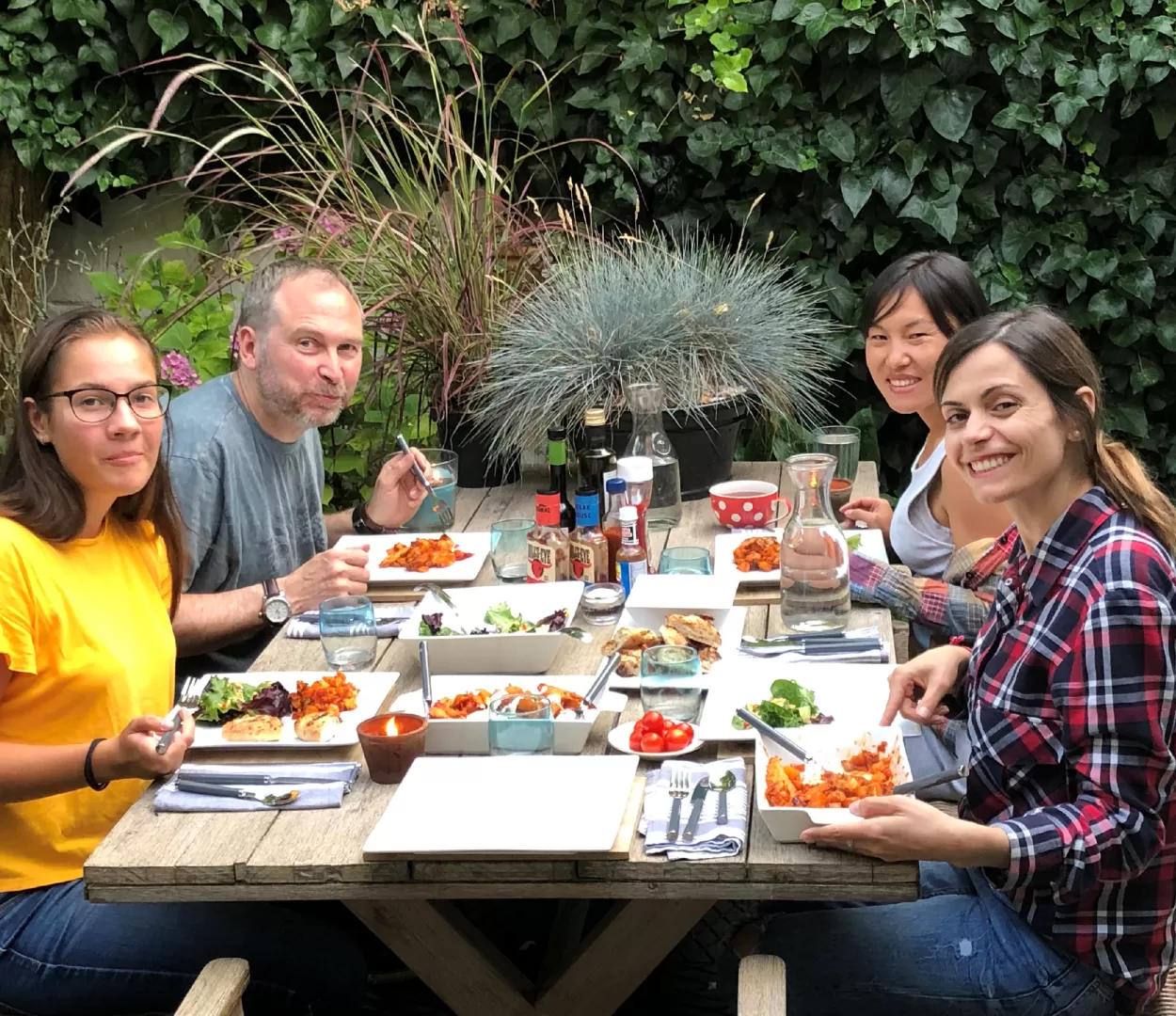 A photo of English language students from ELC Chester enjoying an outdoor meal with their hosts. This image is being used to portray the option where two students (who speak different languages) share a room in a homestay in the UK.