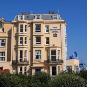 The cream facade of the 5-storey Brighton Hotel with a cloudless blue sky as backdrop.