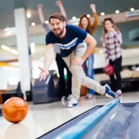 A stock photo of someone bowling. The person has just thrown the bowling ball and it's still in shot, but the people behind are already cheering. Maybe it's encouragement, maybe they know something we don't.
