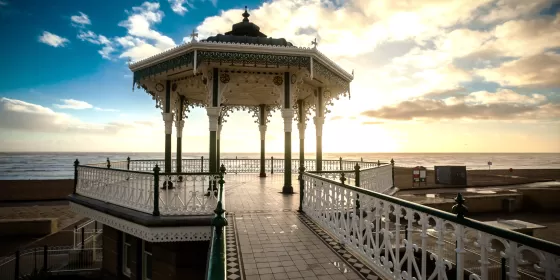 A striking photo of the bandstand on the seafront in Brighton. The structure has been totally renovated and the detailed iron work is silhouetted against the sky.