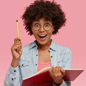 A fun photo of a woman, wide-eyed, holding up a yellow pencil like she's just worked something out or completed something. It's unlikely to be her IELTS writing test, but we're using this image to represent that.