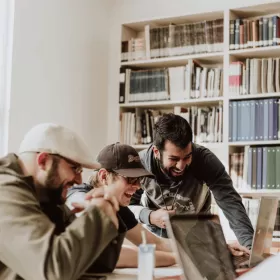 A shot of several young men at work in an office environment. Something has clearly made them laugh. It's probably something on TikTok but they should probably be working.
